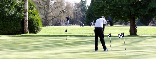 A golfer practices his putts while another warms up his swing at the Langara Golf Course. Photo: Anna Dimoff